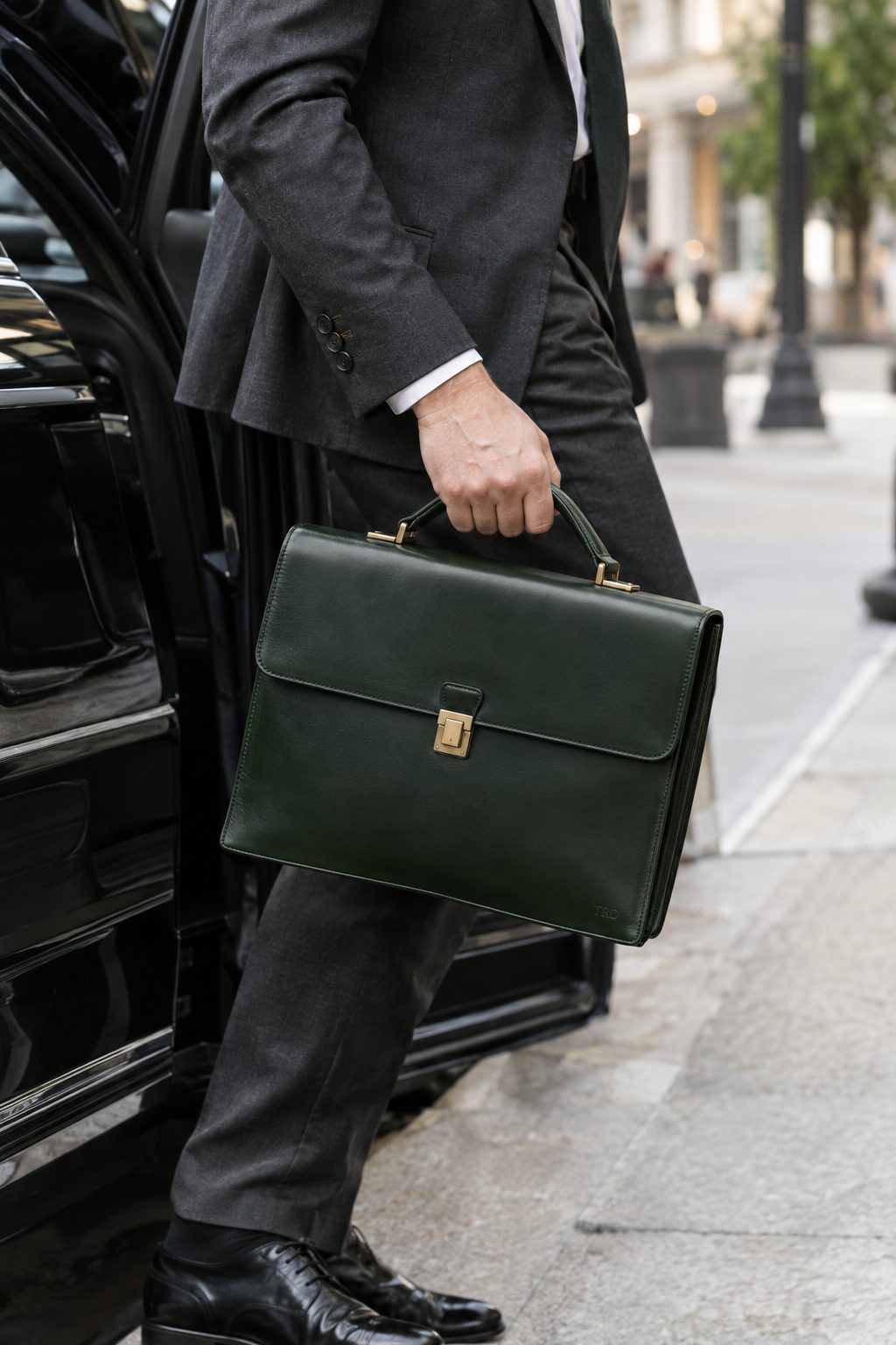 A physician stepping out of a car holding a slim green leather briefcase